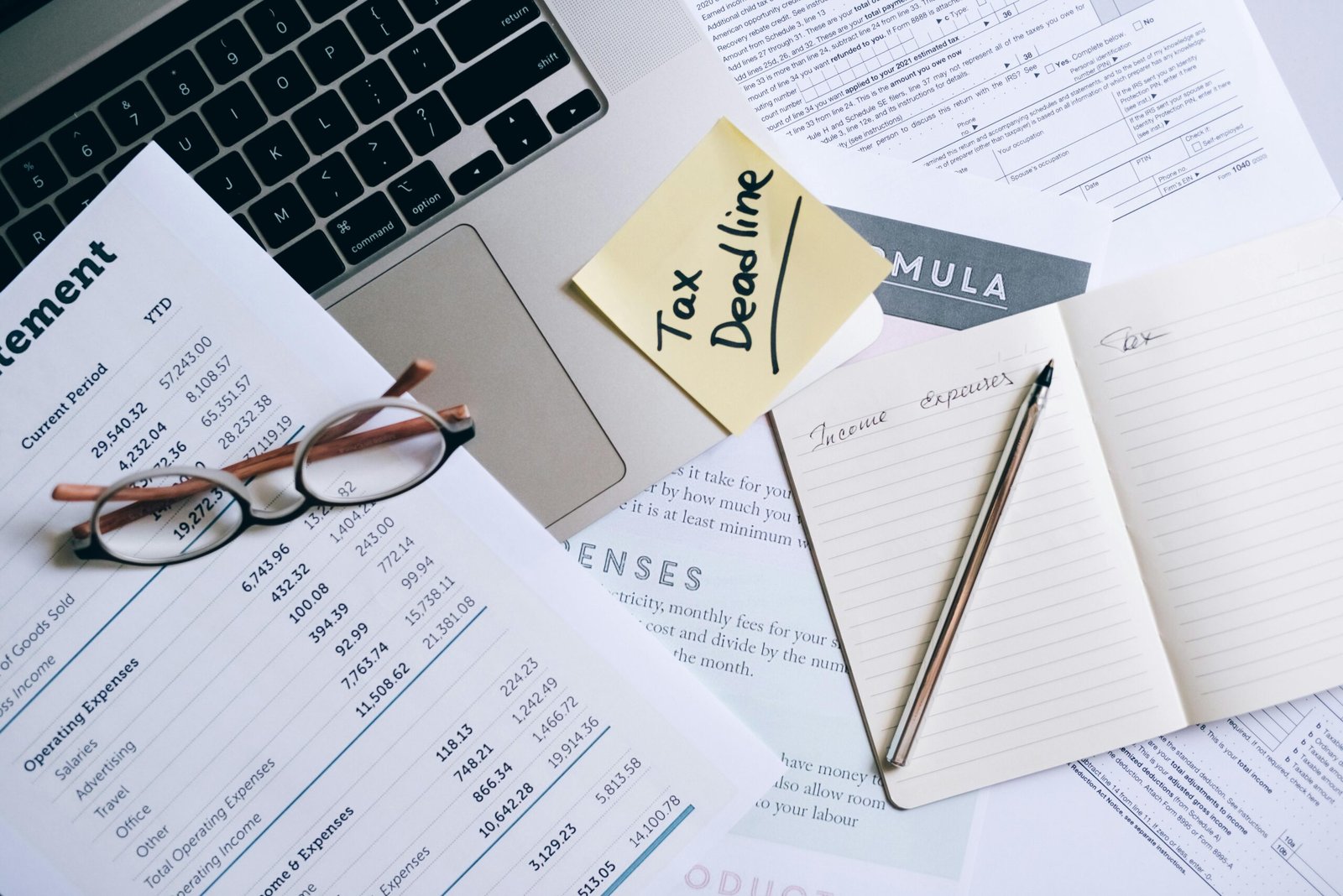 Workspace with laptop, documents, and tax deadline note for financial management.